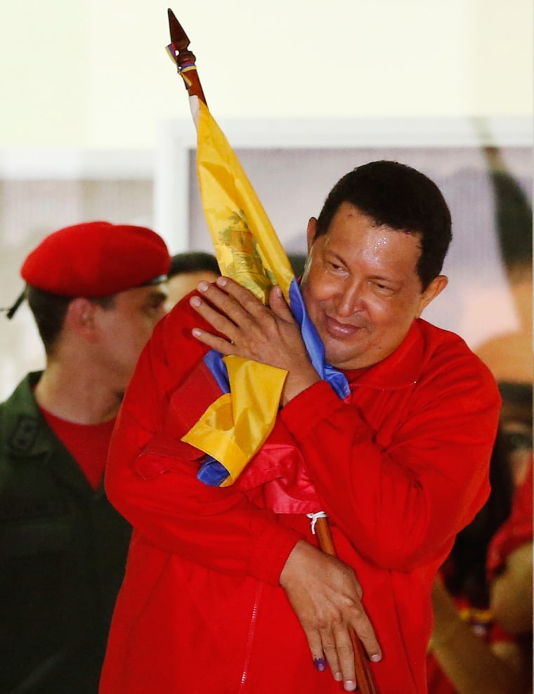 Image: Venezuelan President Hugo Chavez hugs the national flag while celebrating from a balcony at the Miraflores Palace in Caracas